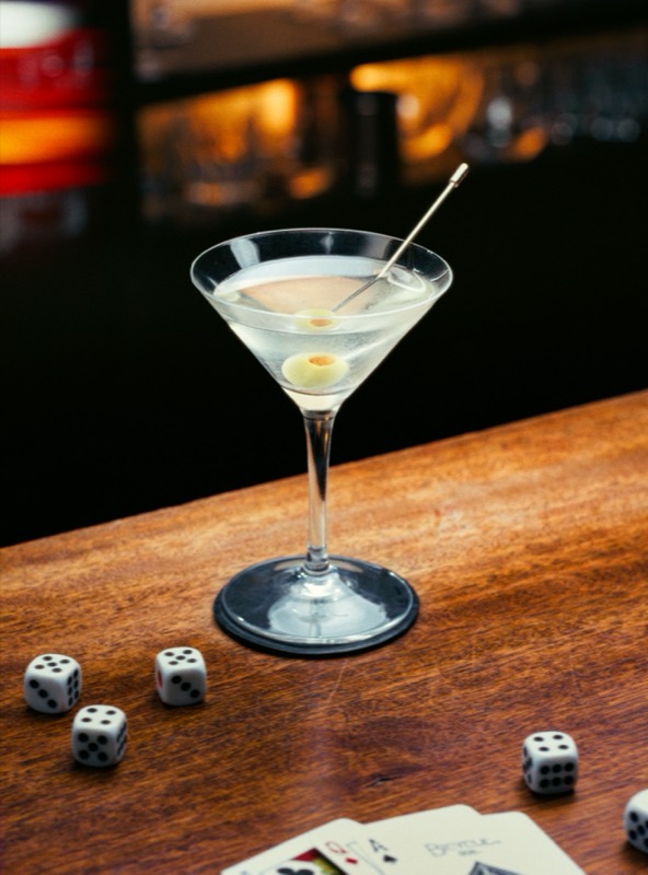 Martini with olives beside scattered dice and playing cards, shot for Music Bar Nightfly